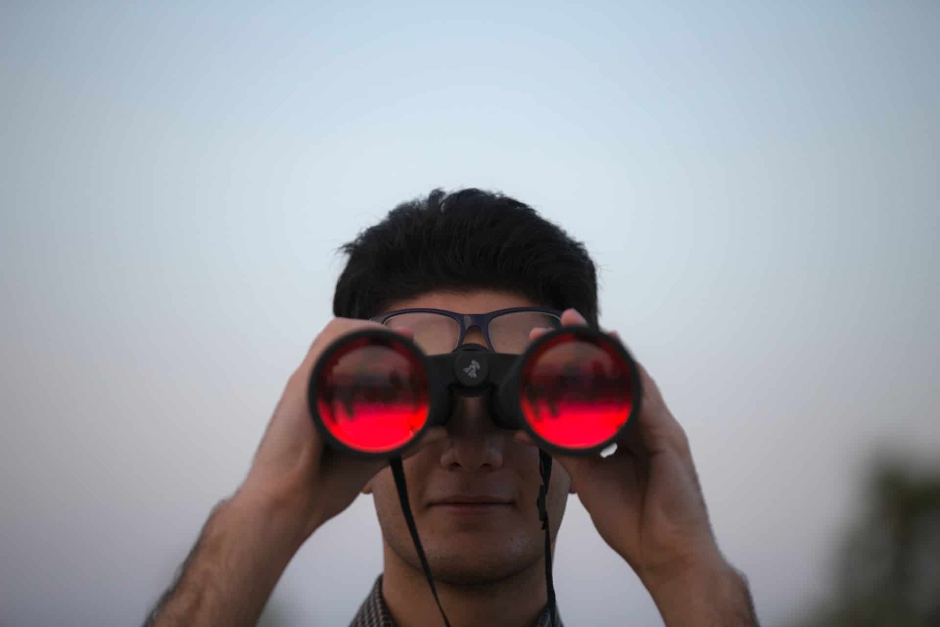 a guy using binocular with red lences 