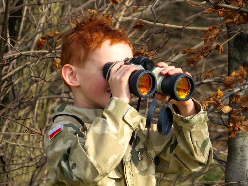 Child in military uniform using binoculars