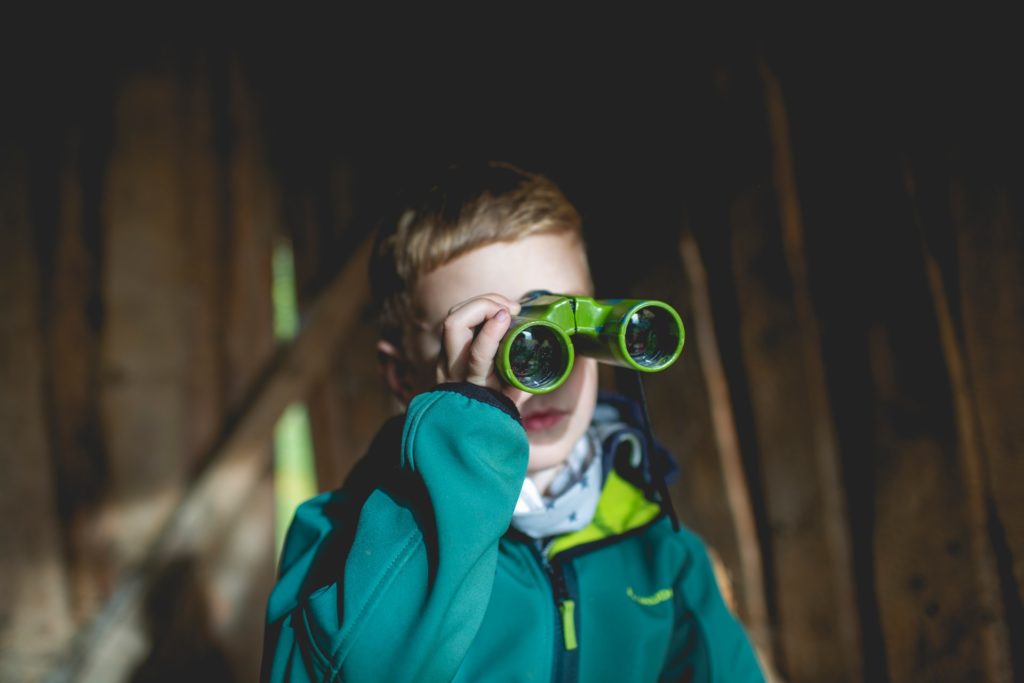 a kid looking through a pair of small green binoculars