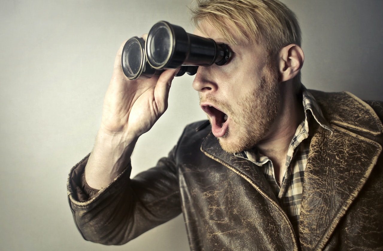 A man looking through a binocular in surprise