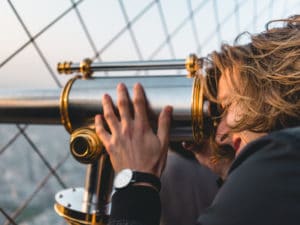 a man withy long hair using binocular