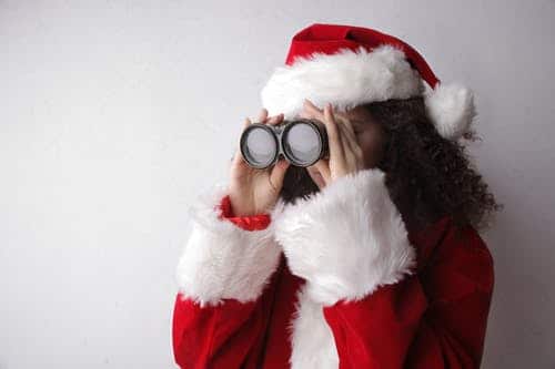 a girl wears santa costume using binocular 
