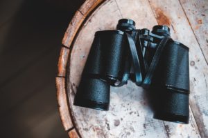Black binoculars on a brown wooden table