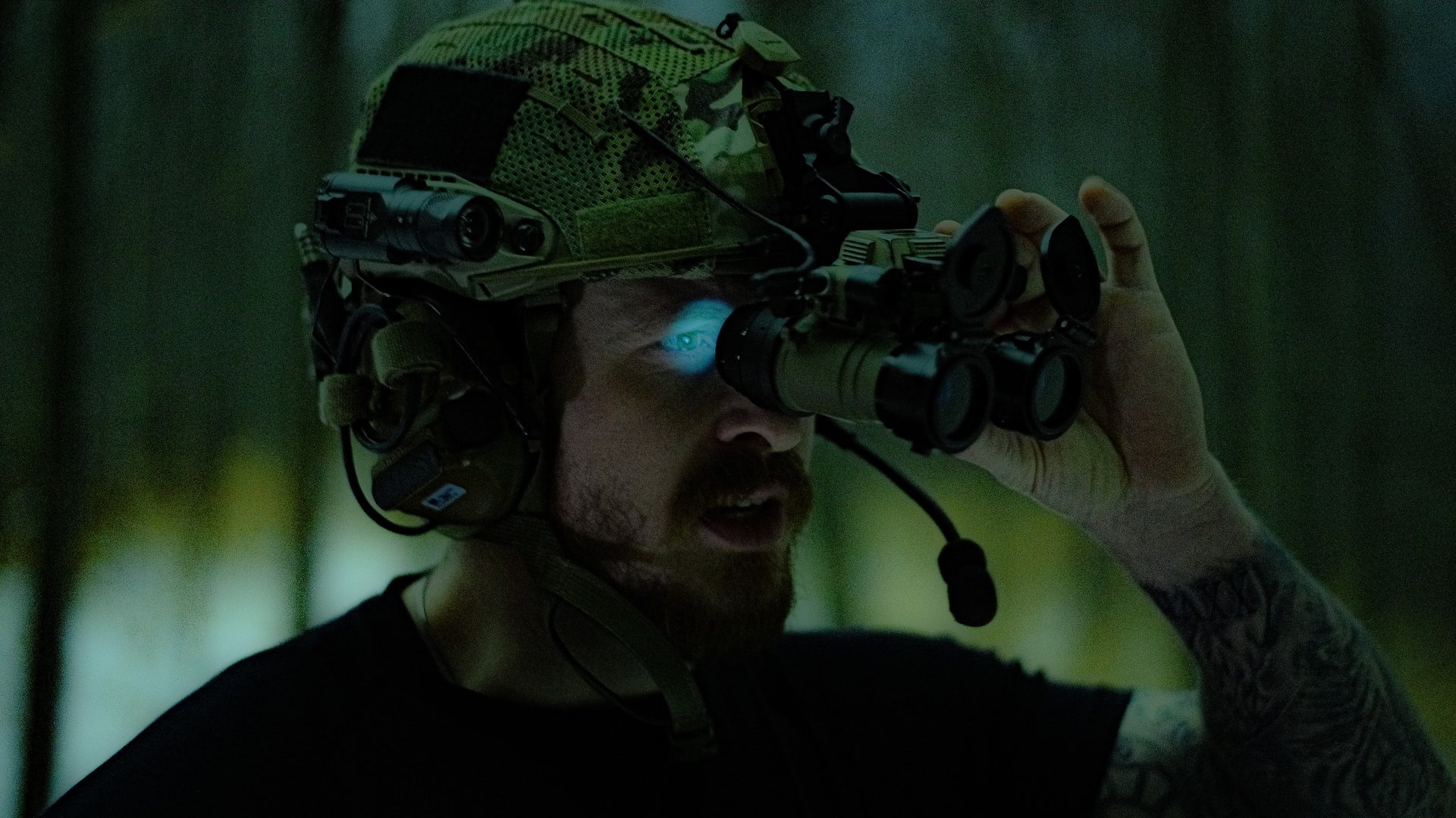 A military man staring through head-mounted binoculars