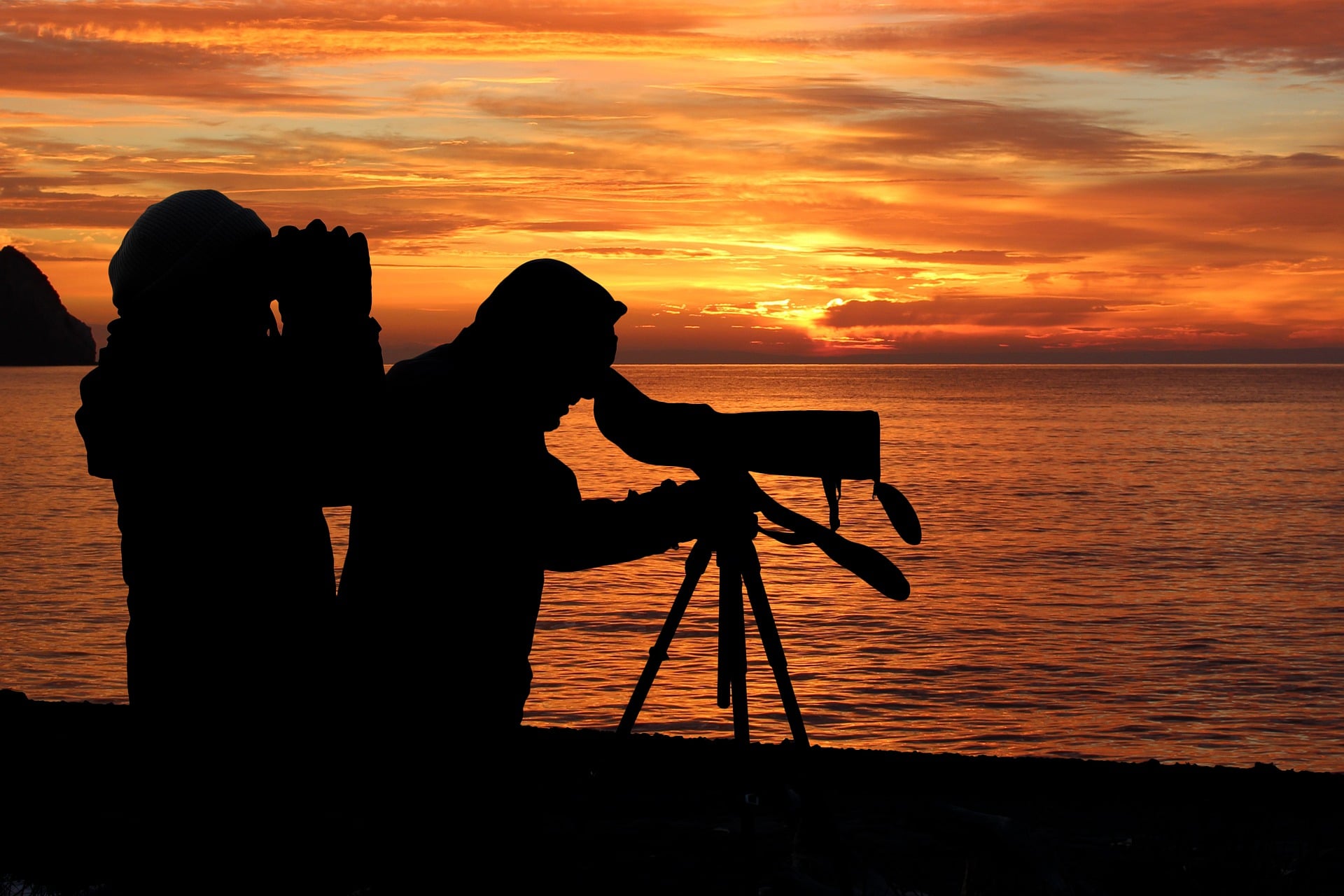Silhouettes of a man and woman using binoculars